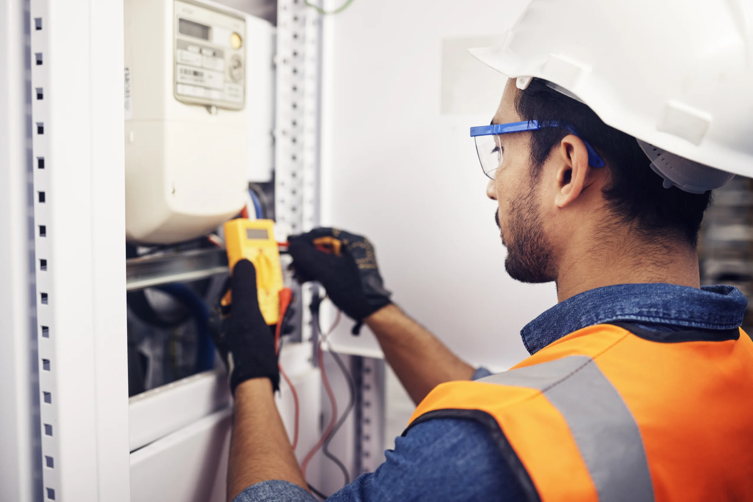 Technician, man and multimeter testing power for electricity, energy inspection and electrical system. Electrician, engineering and voltage test tool for machine, industrial mechanic and control room